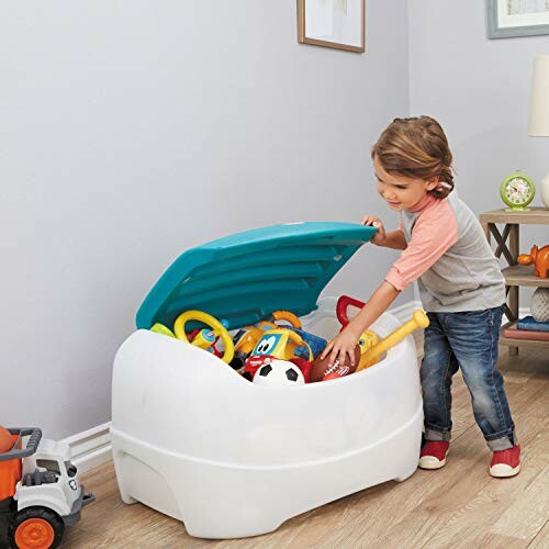 Child opening a toy box filled with various toys.